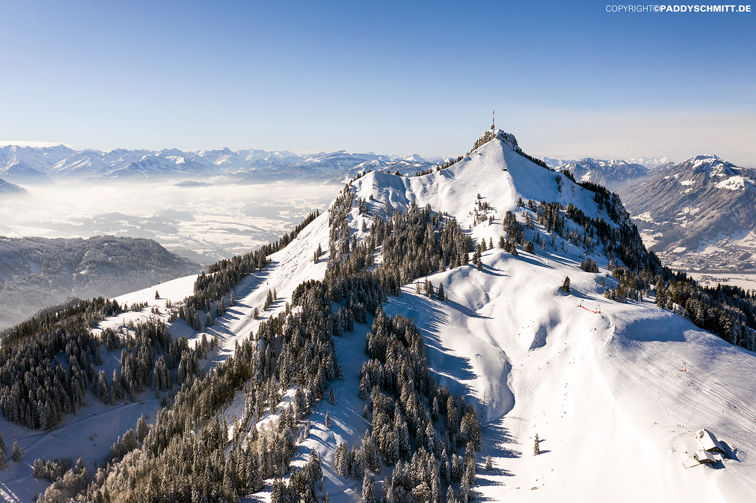 Der verschneite Berg Grünten aus der Ferne mit dem Bergpanorama der Allgaeuer Alpen im Hintergrund.